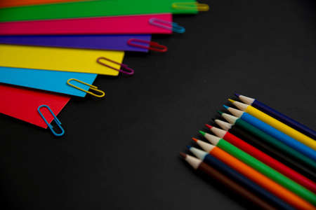 Colored pencils in a row on a black sheet of paperの写真素材