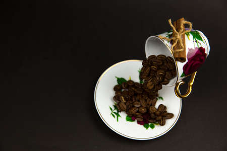 Coffee beans sprinkled from a coffee cup. Black background.の写真素材