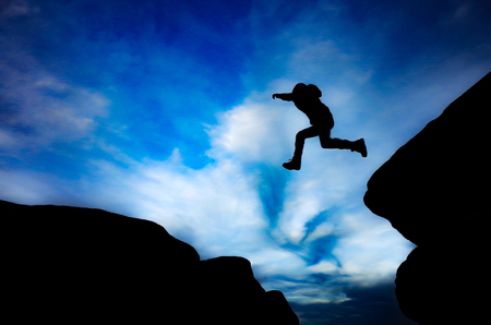 Silhouette of boy Jumping between rocksの写真素材