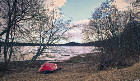 Beautiful winter seasonal photograph. Small island in the archipelago with large trees, green vegetation and a small boat/vessel with red color resting during the winter.の写真素材