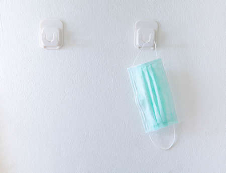 Green medical face mask holding on the old wall with copy space. Concept of reuse and recycle due to lack of medical mask during coronavirus pandemic crisis.の写真素材