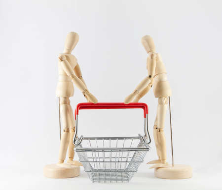 Wooden figurines holding shopping basket on white background. Shopping and marketing conceptの写真素材