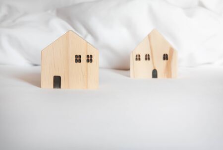 Small wooden house model on white bed. Selective focus with copy space. Home, housing, mortgage loan and real estate concept.の写真素材