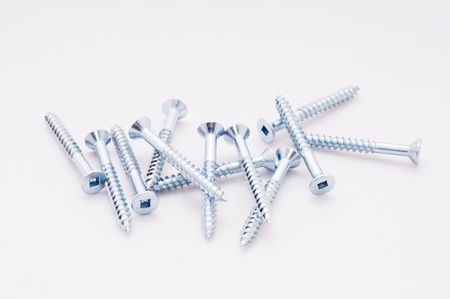 A pile of screws lay on a white backgroundの写真素材