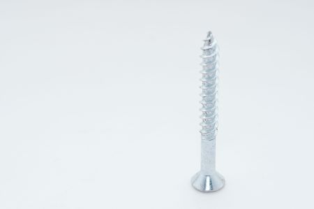 A macro picture of a screw stands on its head on white with room for copy spaceの写真素材