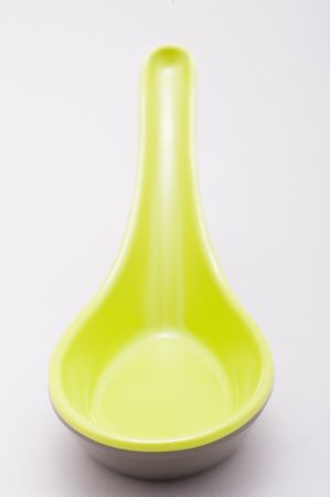A green asian spoon sits on white from a wide agle perspective の写真素材