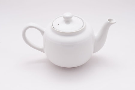 A white teapot sits sideways on white with room for copyspaceの写真素材