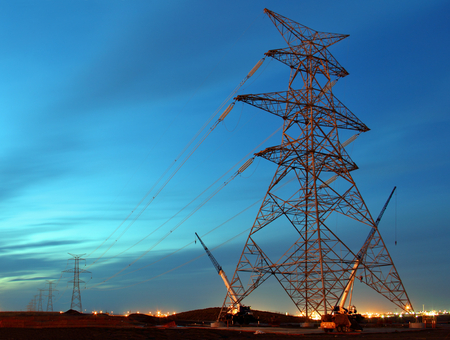 Electric tower under construction with crane at night fall, dawn.の写真素材