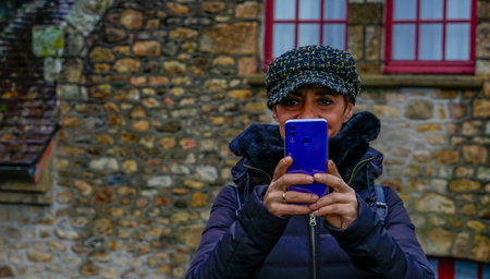Capped girl taking a picture with her cell phone