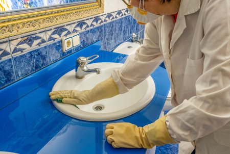 worker with mask and gloves disinfecting and cleaning virus sinks with Coronavirus, pandemic concept.の写真素材