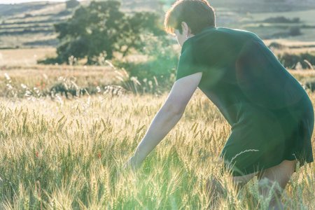 woman in a dark green dress in a wheat field in the summer at sunset
