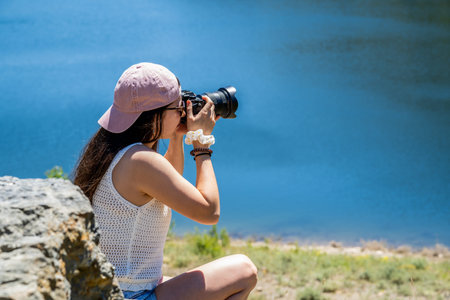 young girl taking professional photos at the edge of a lake on summer vacation