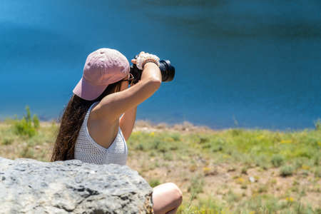 young girl taking professional photos at the edge of a lake on summer vacationの写真素材