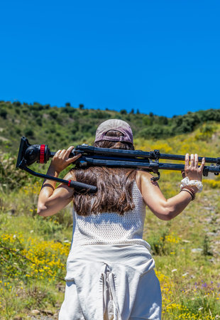 girl with a professional tripod of photography and video walks on the mountain in summer