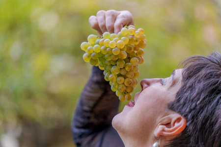 Woman with a bunch of white grapes in her hands ready to enjoy this rich delicacyの写真素材