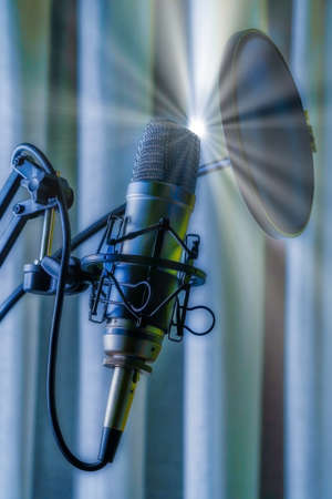 Studio condenser microphone with anti-pop filter and anti-shake mount with colored backlight blue. Side viewの写真素材