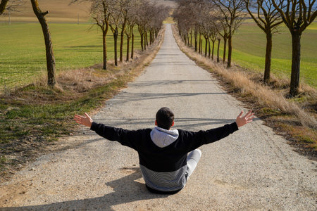 young man sitting on a lonely roadの写真素材