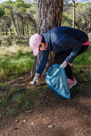 hiker picking up litter in the pine forestの写真素材