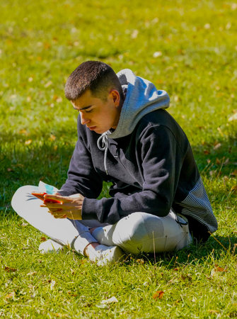 Young boy sitting after a day's study looking at his mobile phone and answering his messages.