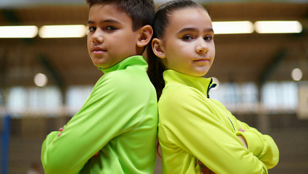 Portrait of two children wearing sportswear standing back to backの素材