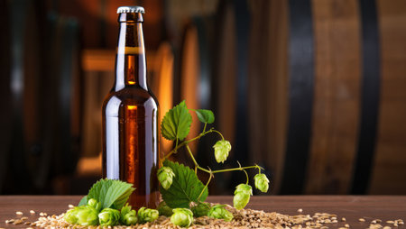 Bottle of beer with hop cones on wooden table and barrel backgroundの素材