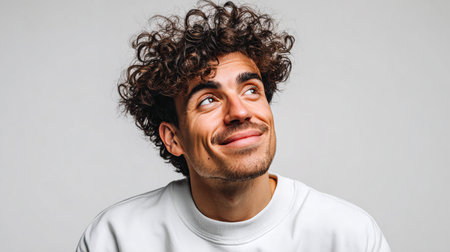 Portrait of a handsome young man with curly hair on a gray backgroundの素材