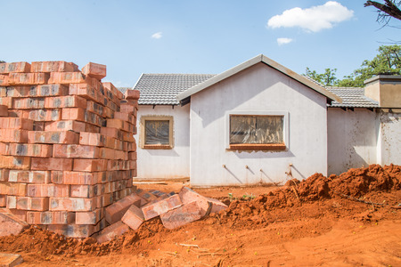 Building material stacked next to the imcomplete house that it is intended for.の写真素材