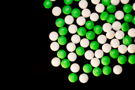 Green and white mints scattered on a black background.の写真素材