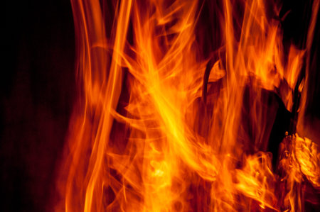 An up close view of the flames of a camp fire, revealing the orange, yellow and red colours of the...