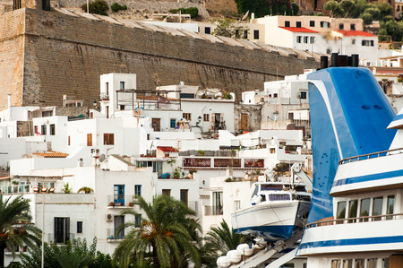The funnel of a luxury yacht and a tender boat are in view in front of the old town of Ibiza island in the Medeteranean.のeditorial素材