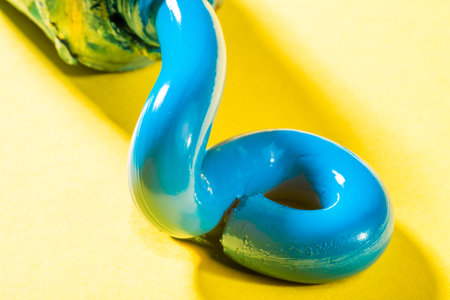 Cerulean Blue Oil Paint is queezed fresh from the tube on to a yellow surface