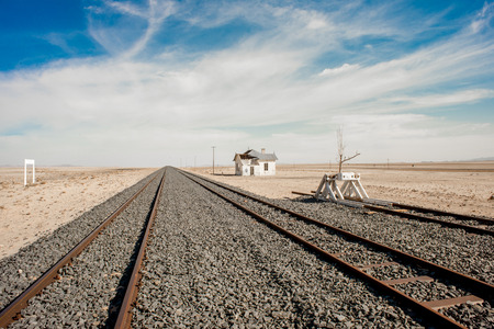 An abandoned house stand by the side of railroad tracks in the desert.の写真素材