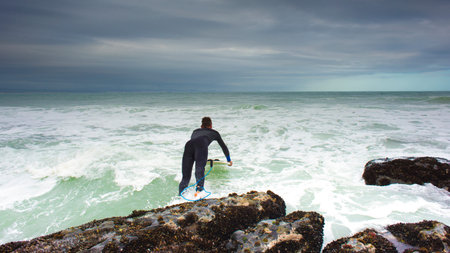 A surfer takes the final leap in to the surf from the rocks at The Point in Jeffreys Bay.