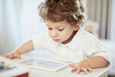 Cute boy in white t-shirt, watching fairy tale - light background. Lovely little scientistの写真素材