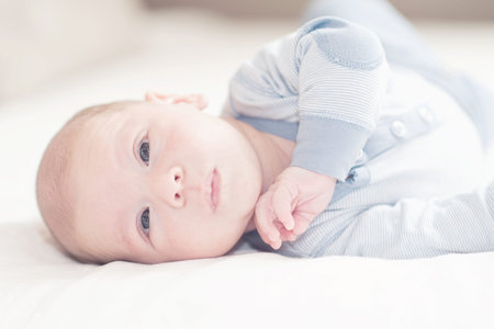 Pretty newborn baby boy in blue lying on a bed