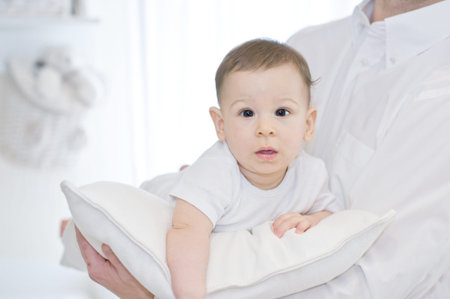 Portrait of a father with his lovely baby boy on white pillow