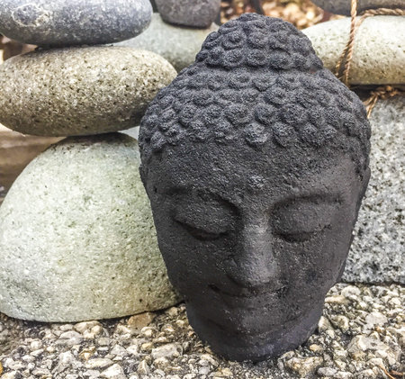 A Zen Moment with a  Buddhist Stone Statue and stones stacked on top of one another  in a rock gardenの写真素材
