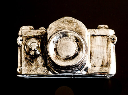 A modern version of a camera in silver and gold with black backgroundの写真素材