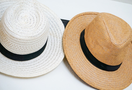 Brown and White Fedora hats hung on a hook with a white backgroundの写真素材
