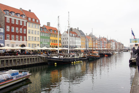 COPENHAGEN, DENMARK. APRIL 15, 2019: Panoramic view of Nyhavn canal in Copenhagen with boats and ships and people walking down the street.のeditorial素材