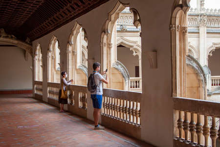 Toledo, Spain. August, 2020. A family wearing face mask to avoid Covid-19 takes photos and stares fixedly at the cloister of the Monastery of San Juan de los Reyes in old town Toledo.のeditorial素材