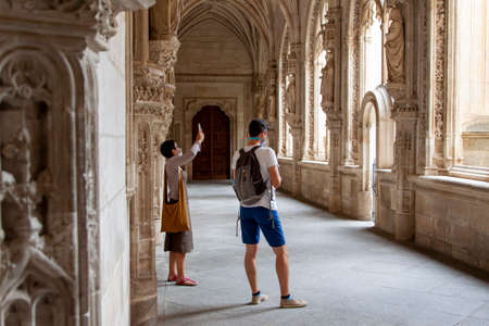 Toledo, Spain. August, 2020. A family wearing face mask to avoid Covid-19 takes photos and stares fixedly at the cloister of the Monastery of San Juan de los Reyes in old town Toledo.のeditorial素材