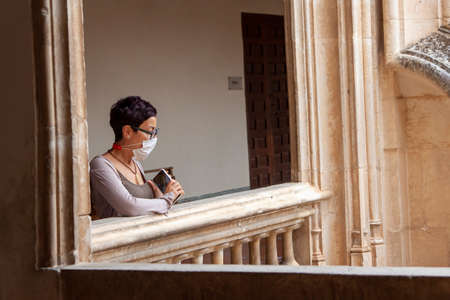 Toledo, Spain. August, 2020. A family wearing face mask to avoid Covid-19 takes photos and stares fixedly at the cloister of the Monastery of San Juan de los Reyes in old town Toledo.のeditorial素材