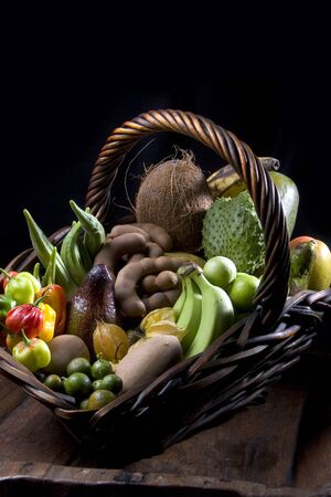 Beautiful basket with tropical fruits with black background.の写真素材