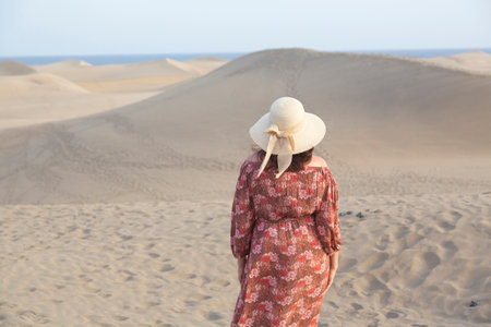 Woman in a hat on the sand dunes watching the horizon.の写真素材