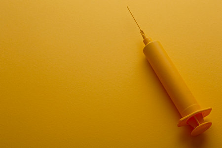 Yellow injection syringe on yellow background.の写真素材