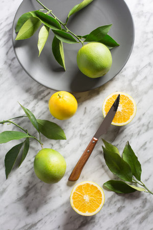 Dish with wild oranges on gray marble background. View from above.