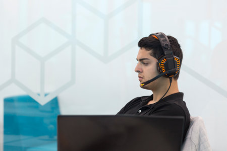 Young man with headphones, sitting in coworking office.の写真素材