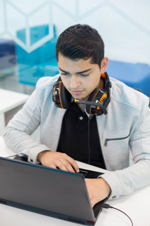 Young man with headphones, working on the computer in coworking office.の写真素材