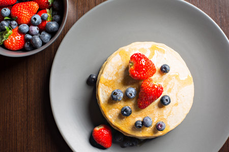 View from above of classic American pancakes, with strawberries and fresh blueberries and syrup.の写真素材